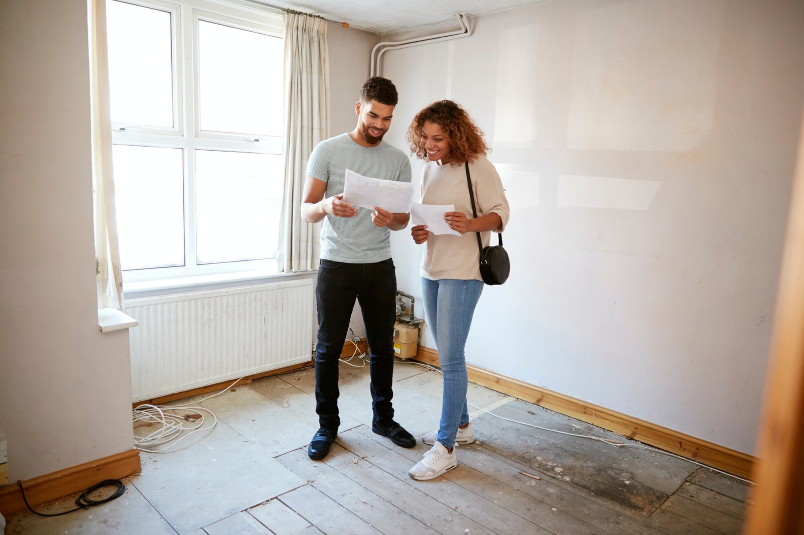 couple-buying-house-for-first-time-looking-at-house-survey-in-room-to-be-renovated